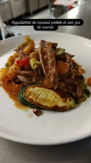 Plat de viande grillée avec légumes variés et sauce, servi dans une assiette blanche.